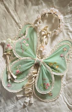 two pieces of clothing laying on top of a white sheet covered in lace and flowers