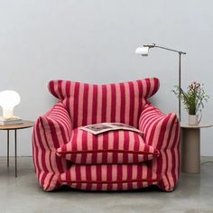 a red and white striped chair sitting next to a table with a lamp on it