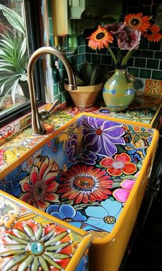 a colorful sink in front of a window with potted plants