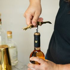 a person opening a wine bottle with a corkscrew