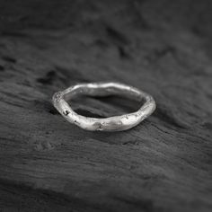 a silver ring sitting on top of a piece of wood with no one around it