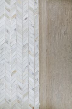 a wooden wall with white and grey herringbones on the wood paneling next to it