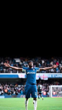 a man standing on top of a soccer field holding his arms out in the air