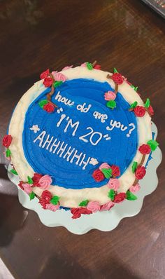 a blue cake with white frosting and red flowers on it sitting on a table