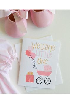 a welcome little one card next to baby shoes