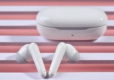 two white earbuds sitting on top of a pink and white striped tablecloth