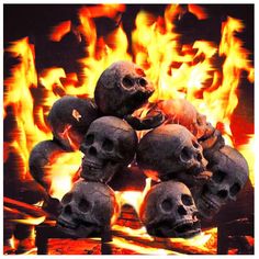 a pile of skulls sitting in front of a fire