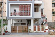 a man standing on the balcony of a two - story house in an urban area