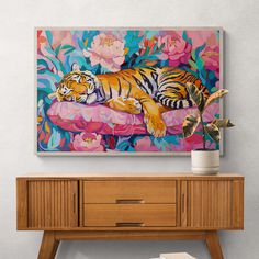 a painting of a tiger laying on top of a pink flowered pillow next to a wooden dresser