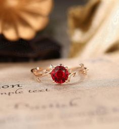 a close up of a ring with a red stone in it on top of a piece of paper