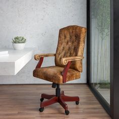 a brown office chair sitting on top of a hard wood floor next to a plant