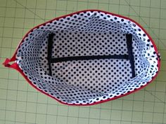 a red and white polka dot bag sitting on top of a cutting board with scissors