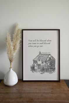 a white vase sitting on top of a wooden table next to a black and white print