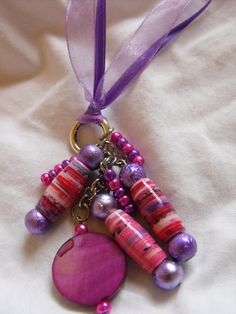 a necklace with beads and a heart hanging from it's end on a purple ribbon