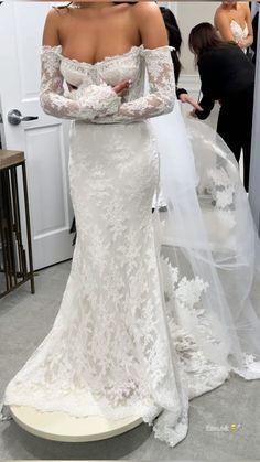 a woman in a white wedding dress with long sleeves