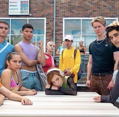 a group of young people standing around a table in front of a brick building with windows