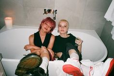 two women sitting in a bathtub with their legs crossed