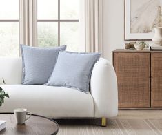 a living room with a white couch and blue pillows on the back of it's sofa