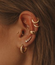 a woman wearing three different types of ear piercings