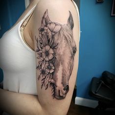 a woman with a horse and flowers tattoo on her arm