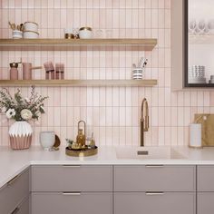 a kitchen with pink tiles and gold accessories on the countertop, along with wooden shelves