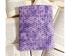 an open book sitting on top of books with purple and gold designs in the pages