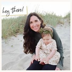 a woman holding a baby on top of a sandy beach next to the words hey there