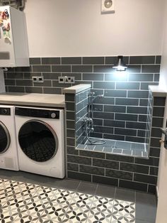 a washer and dryer in a small room with tile flooring on the walls