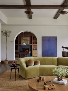 a living room filled with furniture and a grand piano in the corner on top of a wooden coffee table