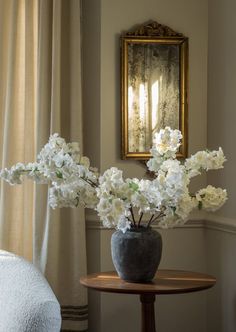 a vase filled with white flowers sitting on top of a table next to a mirror