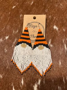 an orange and white beaded earrings with fringes on top of a brown background