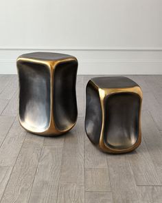 two black and gold stools sitting on top of a wooden floor