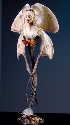 a sculpture of a woman with wings and feathers on her head, holding a bird's tail