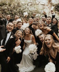 a large group of people posing for a photo with their hands in the air and holding flowers