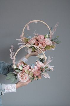 two hands holding flowers in front of a gray wall with the letter o on it