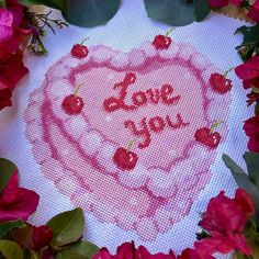 a heart with the words love you painted on it surrounded by pink flowers and leaves