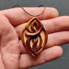 a person is holding a wooden pendant in their hand and it looks like they are made out of wood