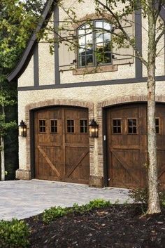 an old photo of two garage doors in front of a house with trees and bushes