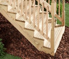 a wooden staircase with handrails and steps in front of some rocks on the ground