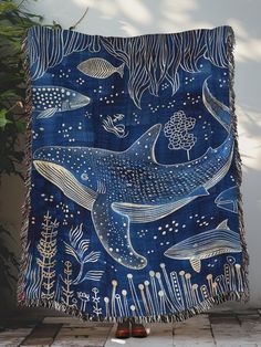 a blue and white blanket with two whales on it, surrounded by seaweed and corals