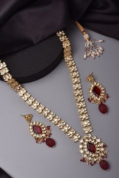 Gold tone lotus pattern long necklace studded with clear and red moissani polki stones. Comes with matching pair of earrings. - Aza Fashions Elegant Red Kundan Necklace For Reception, Elegant Red Kundan Necklace, Red Kundan Necklace With Gemstone, Elegant Red Kundan Jewelry, Red Meenakari Jewelry For Reception, Red Kundan Necklace For Formal Temple Jewelry Style, Elegant Red Kundan Jewelry Sets, Elegant Red Kundan Necklace For Festive Occasions, Elegant Red Meenakari Jewelry