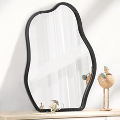 a mirror sitting on top of a wooden dresser next to a toy duck in front of it