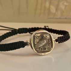 a bracelet with an image of a bird on it and a black cord around the clasp