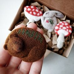 a hand holding a tiny stuffed animal in a box