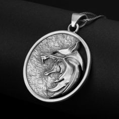 Inspired by a popular TV series, this sterling silver wolf pendant is a captivating accessory for fans and fantasy enthusiasts alike. The iconic emblem represents the fearless monster hunters, drawing on their strength, courage, and determination. With its striking design, this enchanting amulet is the perfect piece for those who appreciate the allure of magic and adventure. Available in four dazzling finishes - oxidized, polished, yellow gold, and rose gold - this unisex necklace offers versati Silver Pendant Jewelry For Fantasy Events, Silver Viking Jewelry For Fantasy Events, Viking Style Silver Wolf Design Jewelry, Viking Style Silver Jewelry With Wolf Design, Hand Cast Fantasy Sterling Silver Jewelry, Silver Fantasy Necklace With Hand Cast, Viking Style Sterling Silver Round Pendant Jewelry, Silver Wolf Pendant Necklace, Silver Wolf Design Round Pendant Necklace