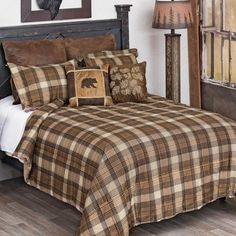 a bed with brown and tan plaid comforter, pillows and lamps on either side