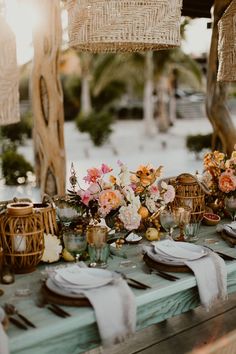 a table set with flowers and candles for an outdoor dinner party or wedding reception at the beach