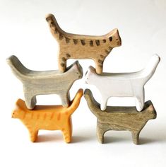 three wooden toy animals sitting next to each other on a white surface with one cat and the other dog