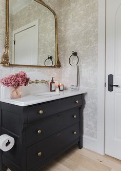 a bathroom with a sink, mirror and toilet paper dispenser