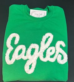 Show your school spirit in this cute sweatshirt. Comfort, casual and loose fitting, made on 50/50 cotton/poly blend shirts.  Embroidered chenille yarn, Eagles sweatshirt.  Show your school spirit in this cute sweatshirt. Comfort, casual and loose fitting, made on 80/20 cotton/poly blend shirts.  Please message us if you have a custom color request and we will create a separate listing for custom requests.  You can follow us at the below link for chances to win giveaways and to see all of our latest creations.  https://www.facebook.com/groups/710060383256657/?ref=share&mibextid=S66gvF You can follow us at the below link for chances to win giveaways and to see all of our latest creations. Pre-shrunk Crew Neck Sweatshirt For School Spirit, Winter College Sweater With School Spirit, Cotton Tops With Embroidered Logo For Fan Gear, Sporty Fall Sweater For School, Collegiate Green Sweatshirt For Football Season, Green Collegiate Sweatshirt For Sports Season, Varsity Fleece Top For Fan Gear, Green Letter Print Sweatshirt For Sports Season, Varsity Cotton Tops For School